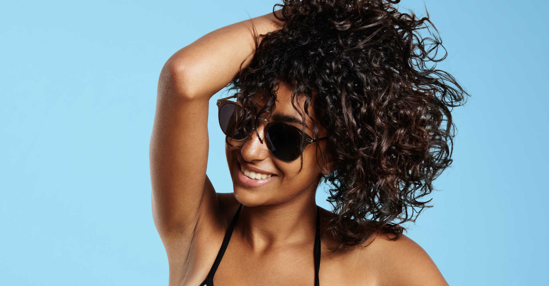 Modelo negra com óculos de sol e cabelos volumosos