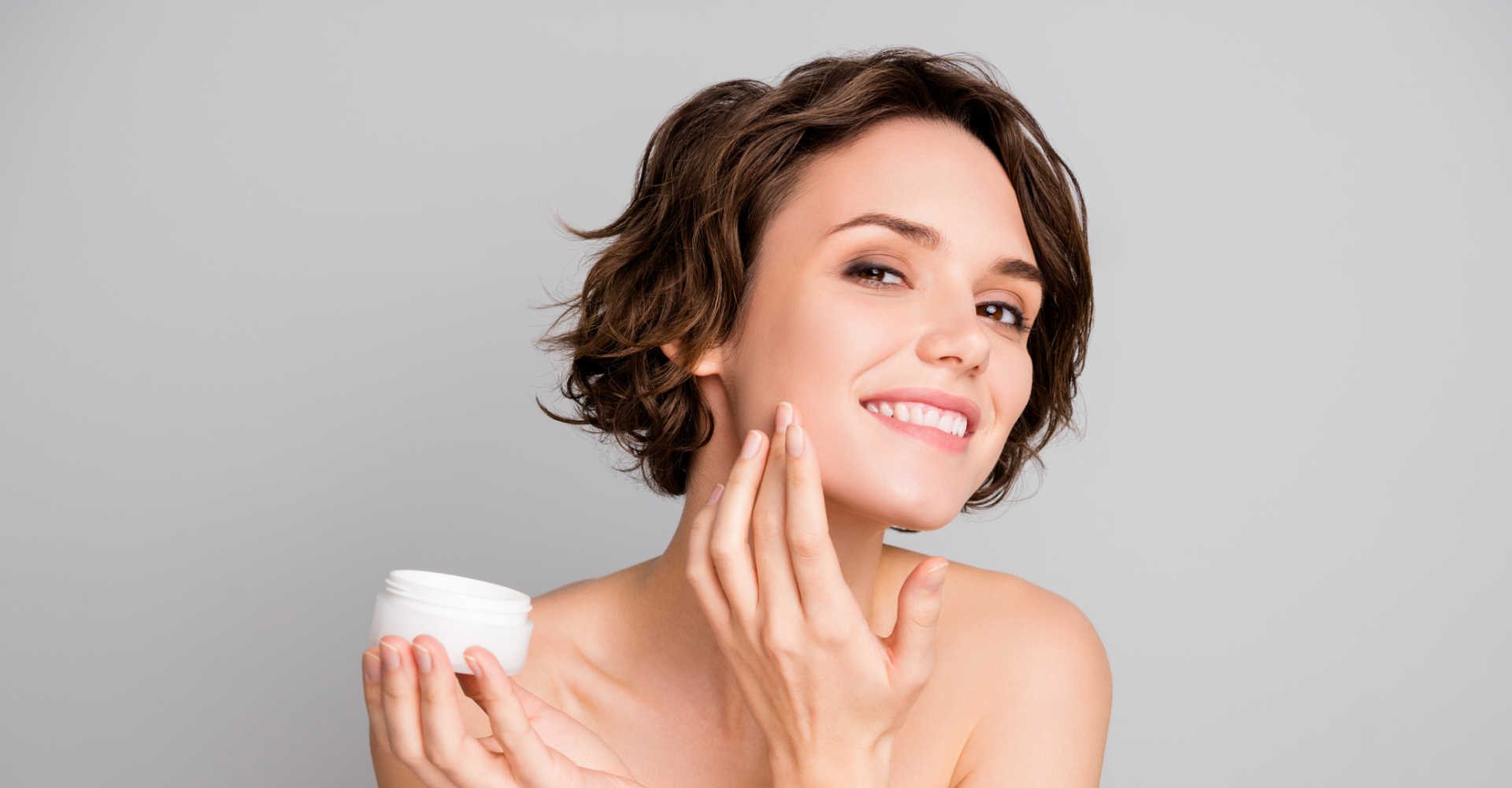 Modelo branca passando creme no rosto