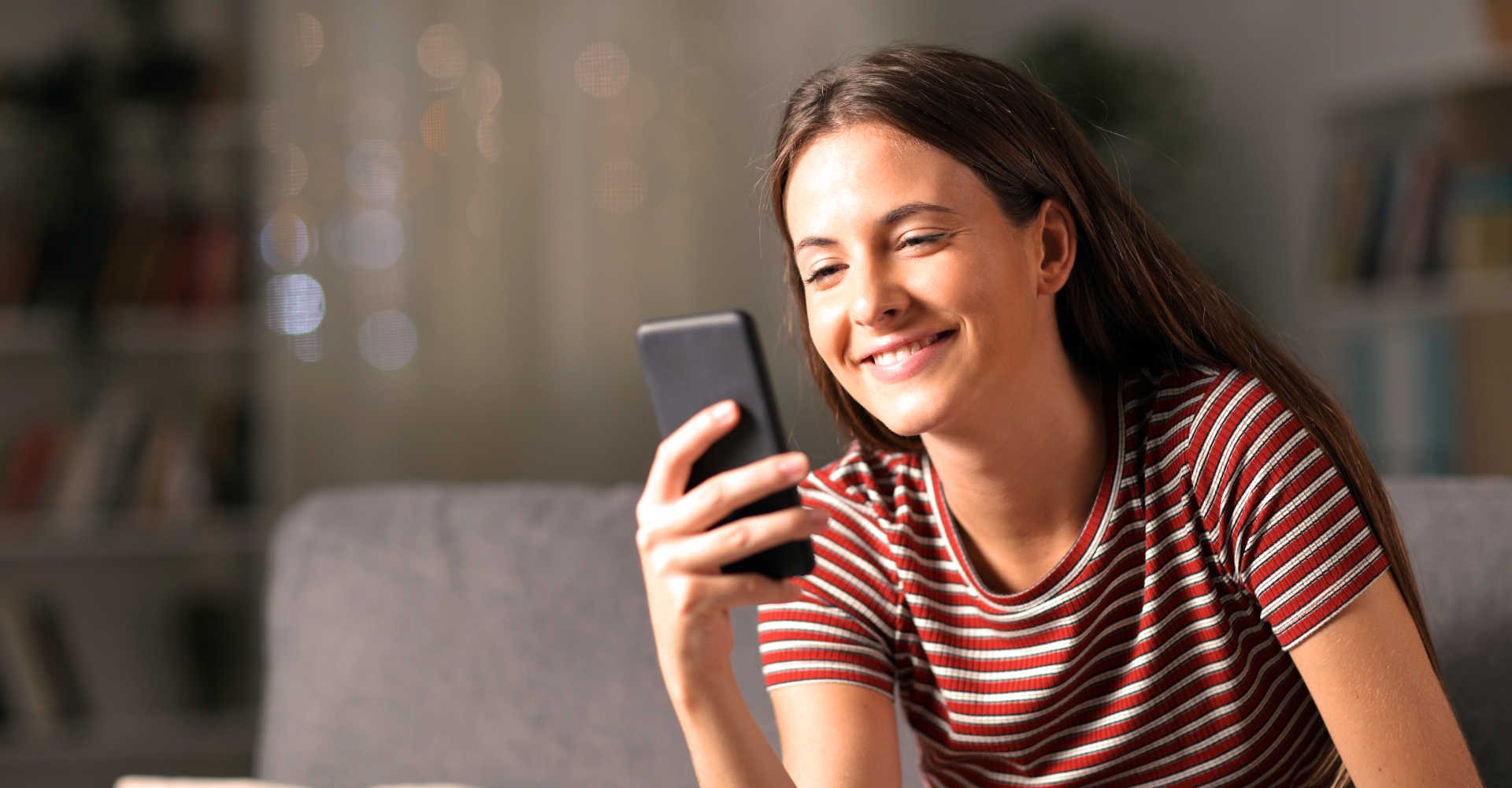 Modelo sorrindo e mexendo no celular