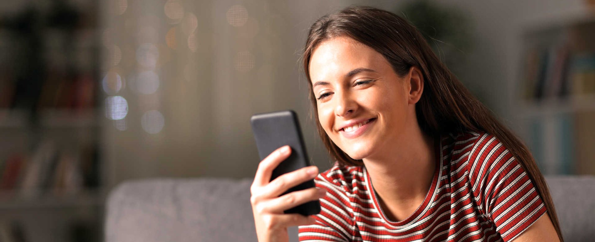 Modelo sorrindo e mexendo no celular