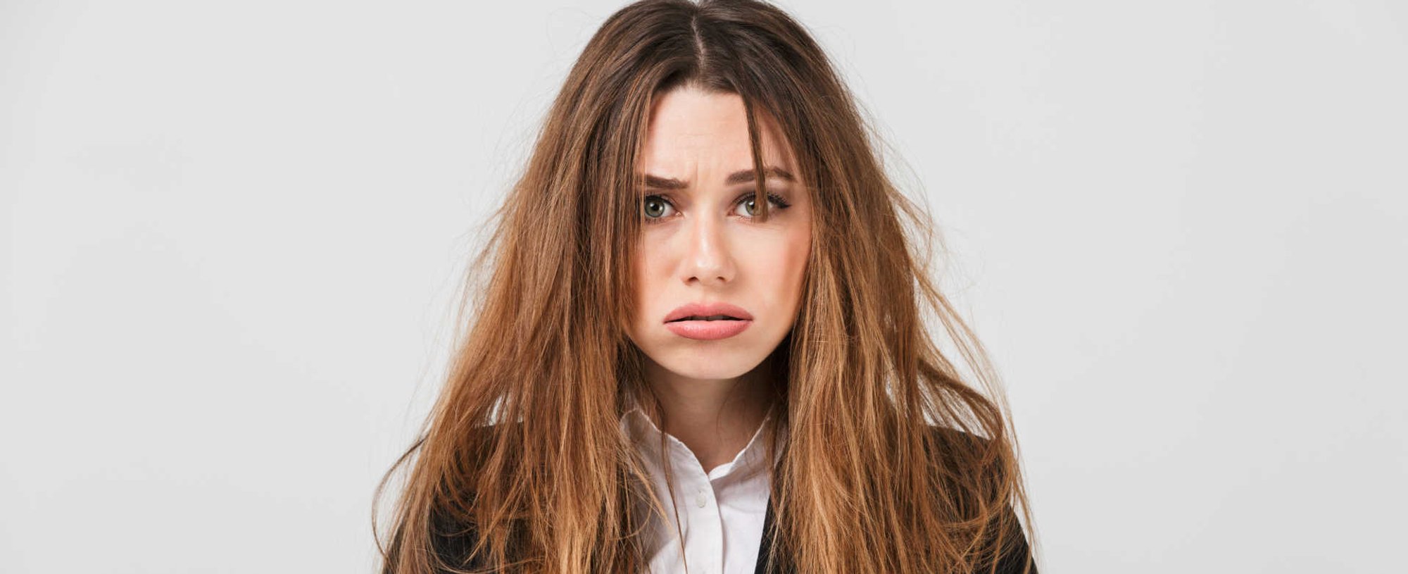 Modelo branca com expressão de tristeza com os cabelos danificados