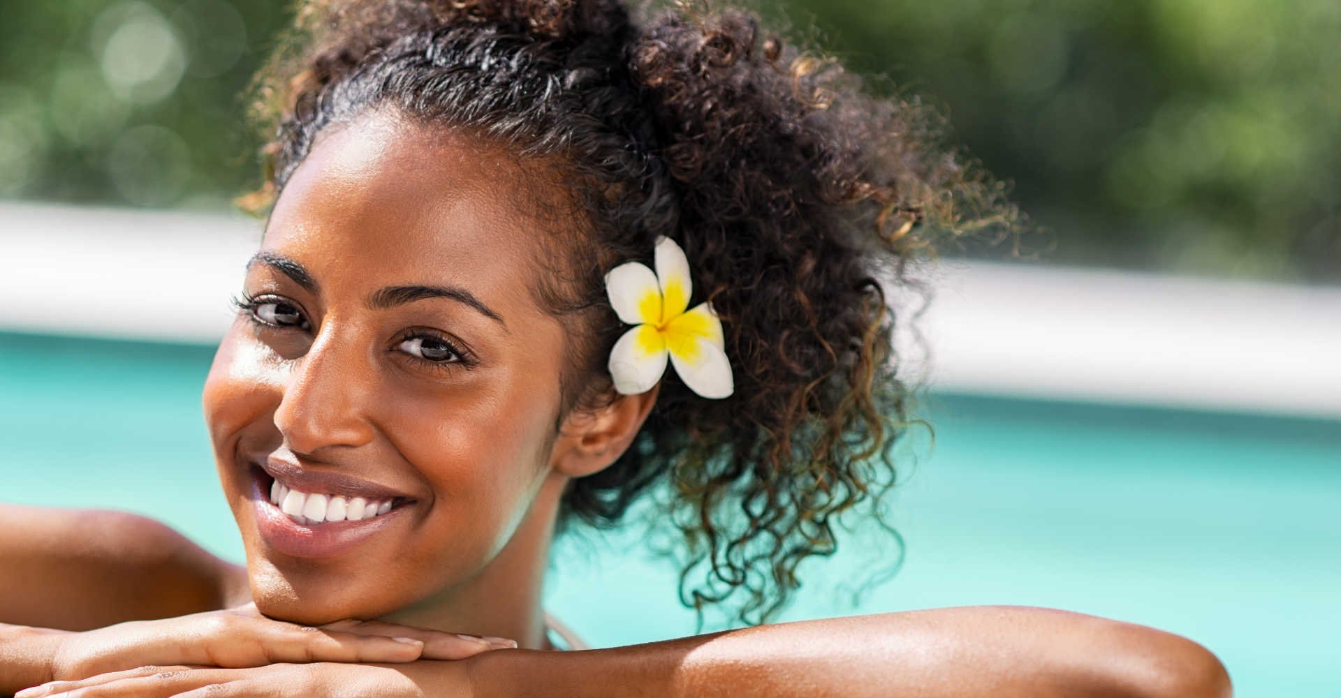 Modelo negra sorrindo com flor na orelha