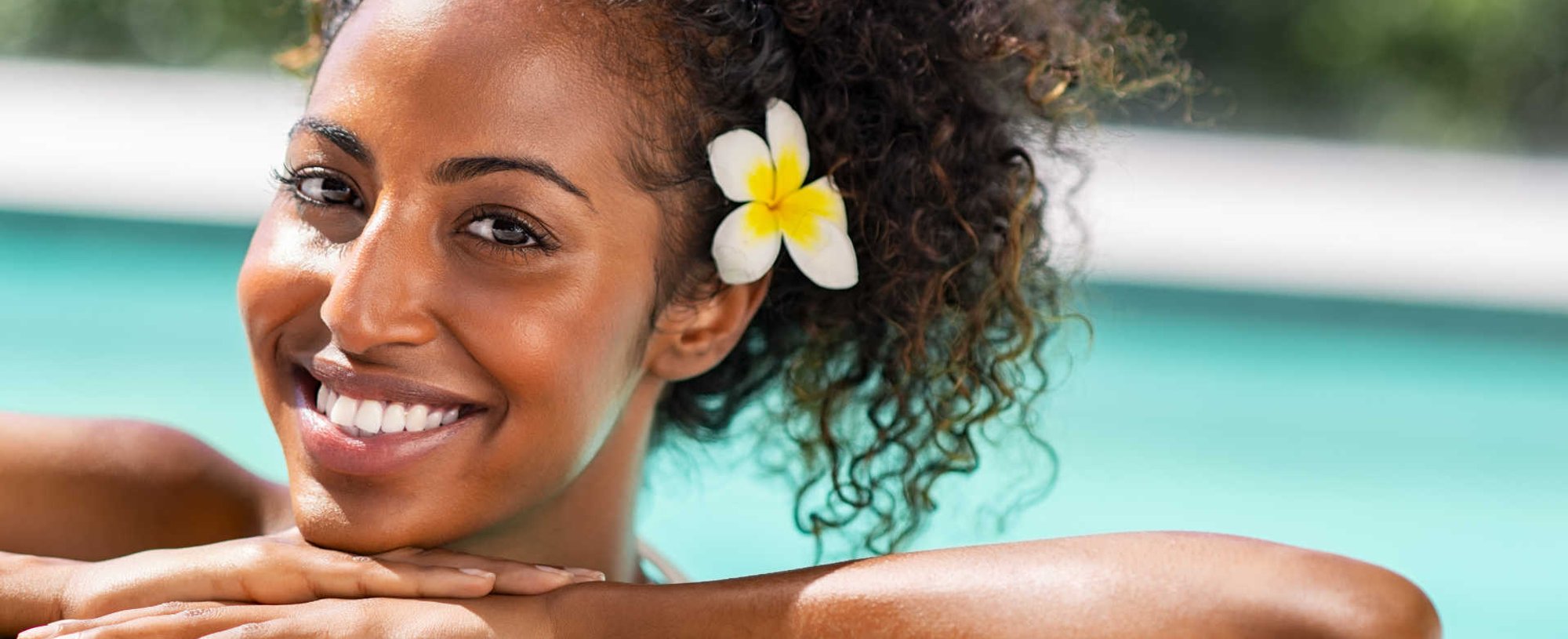 Modelo negra sorrindo com flor na orelha
