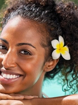 Modelo negra sorrindo com flor na orelha