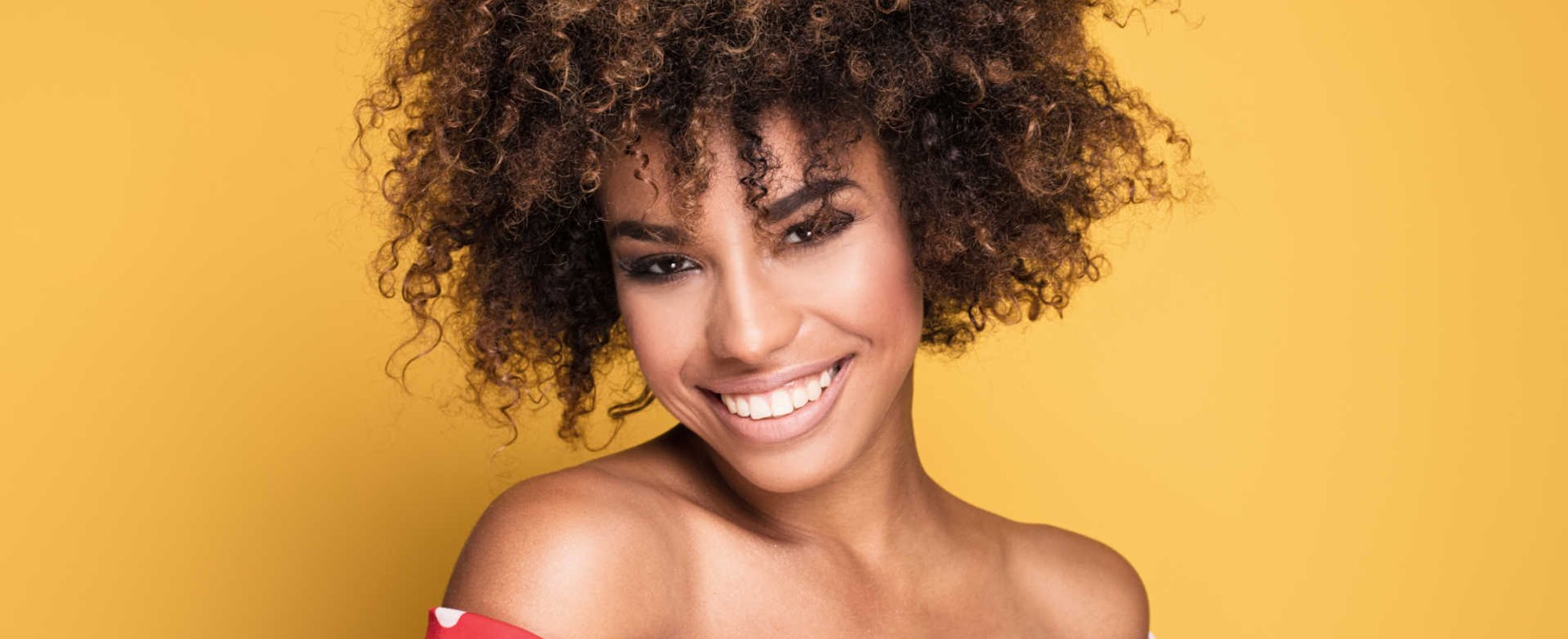 Modelo negra sorrindo com cabelos cacheados