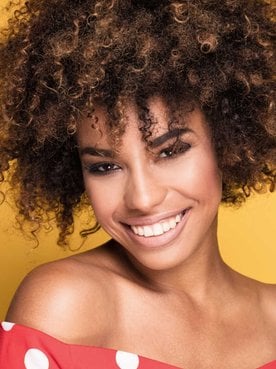 Modelo negra sorrindo com cabelos cacheados