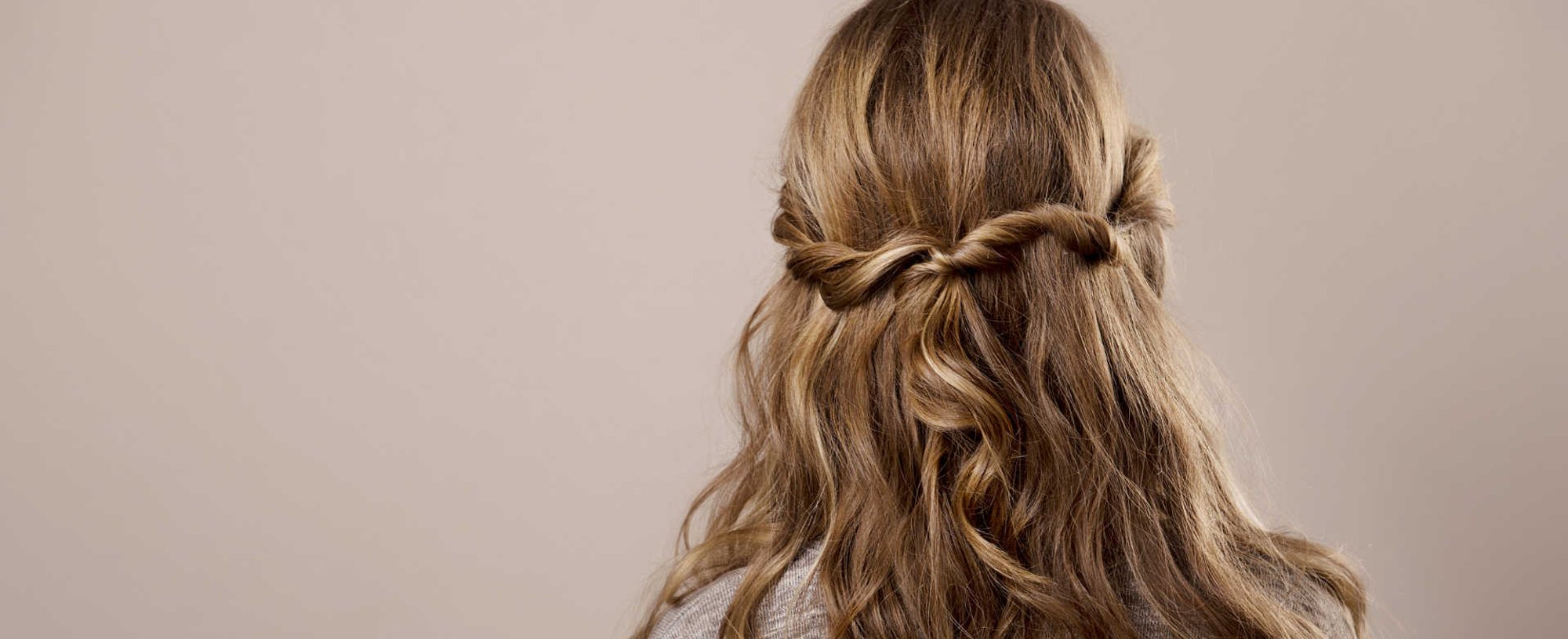 Modelo loira de costas com cabelo trançado semi preso