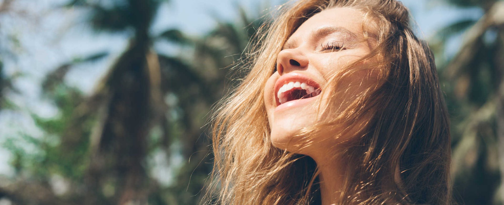 Modelo branca com os olhos fechados e expressão de felicidade no rosto