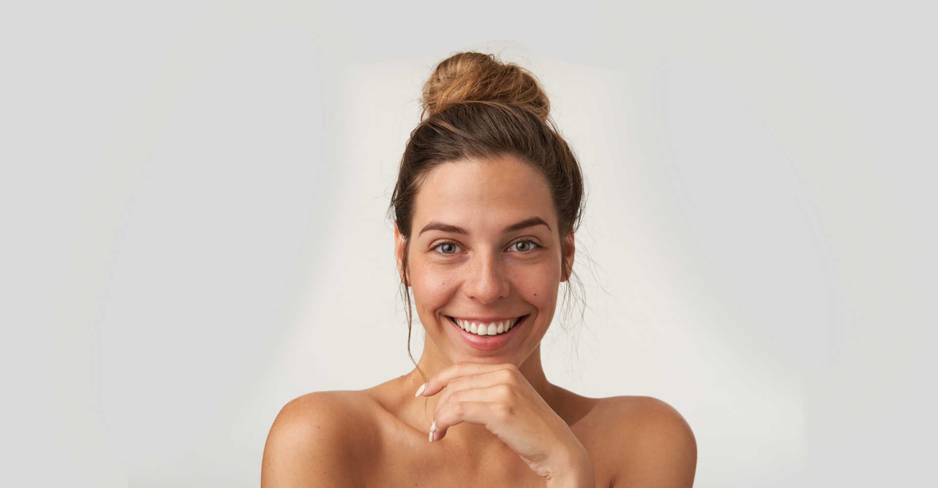 Modelo branca com coque alto sorrindo e posando para a foto