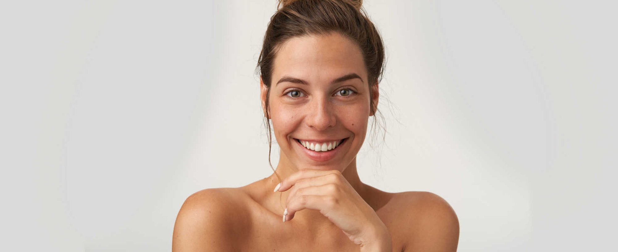 Modelo branca com coque alto sorrindo e posando para a foto