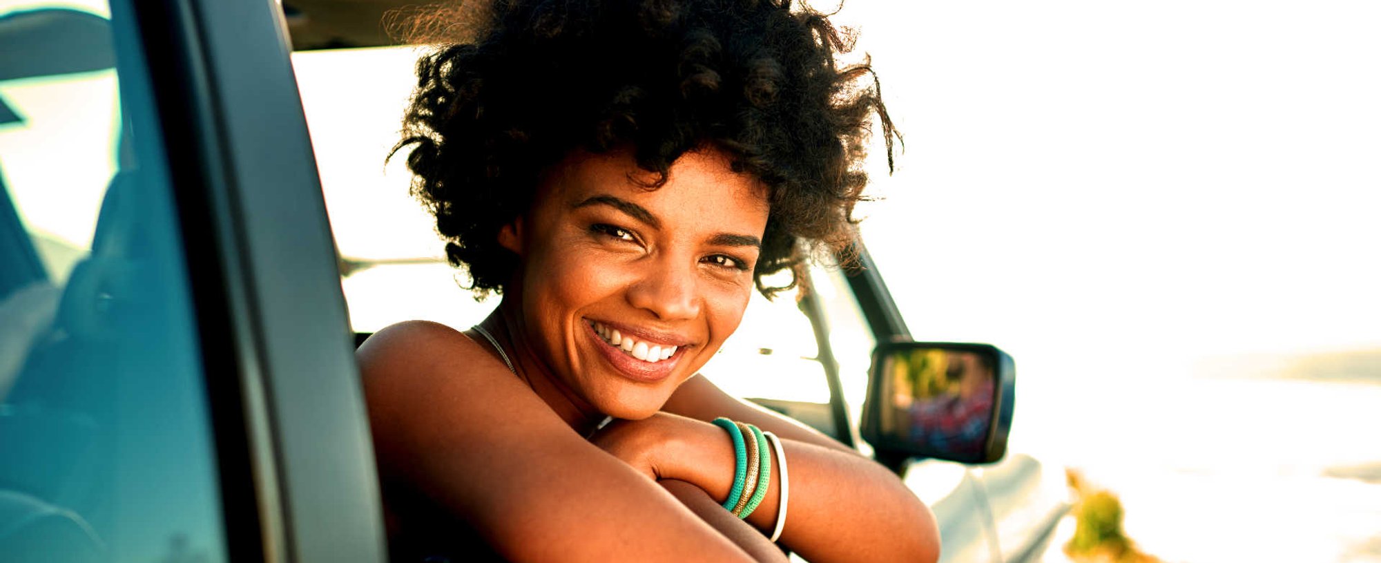 Modelo negra sorrindo com cabelo cacheado