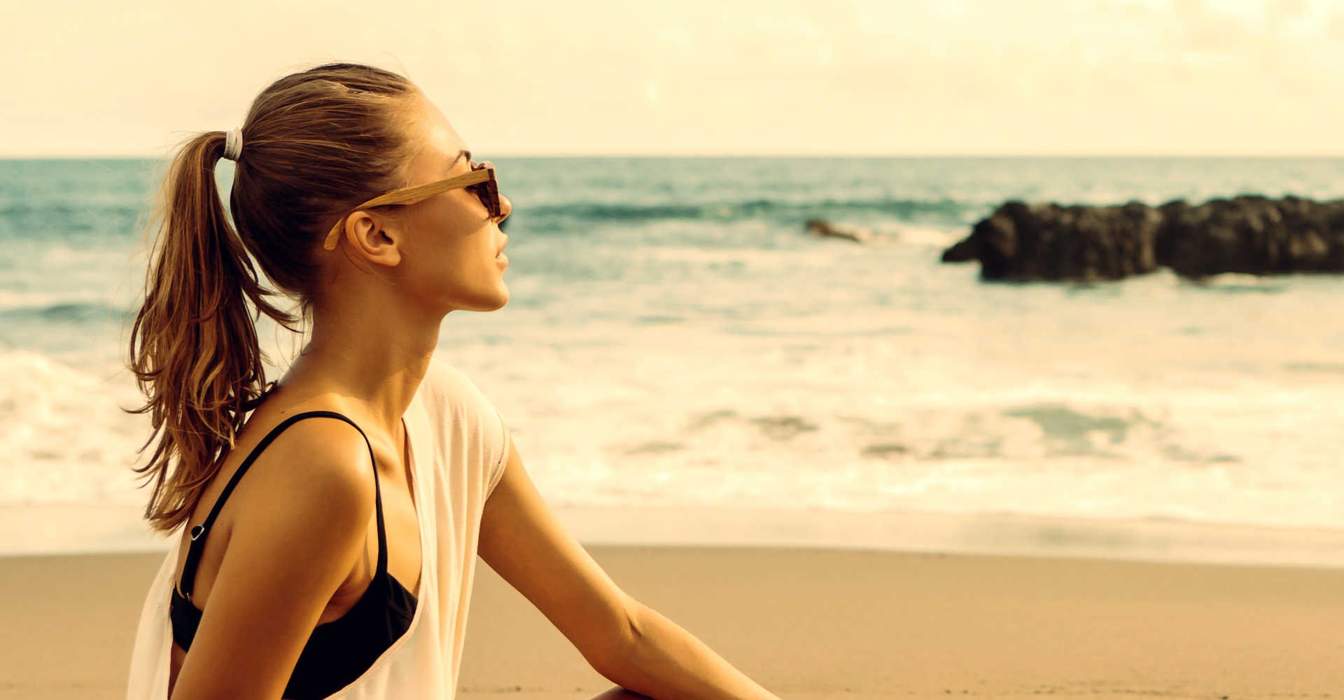 Modelo loira com cabelo amarrado na praia
