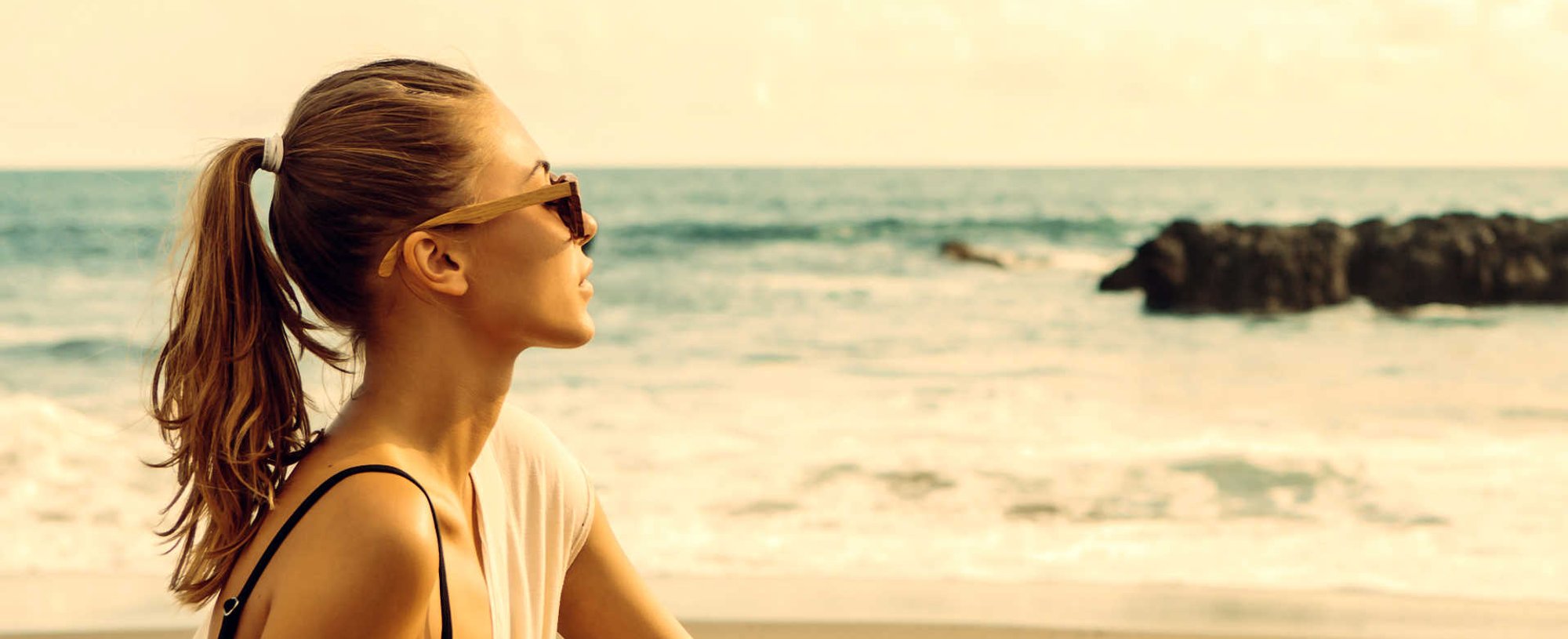 Modelo loira com cabelo amarrado na praia