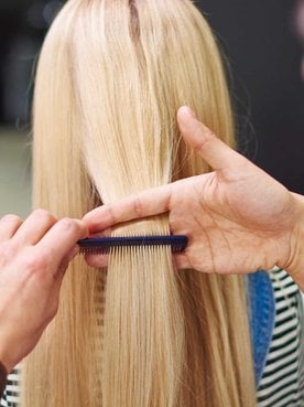Profissional cortando o cabelo de modelo loira