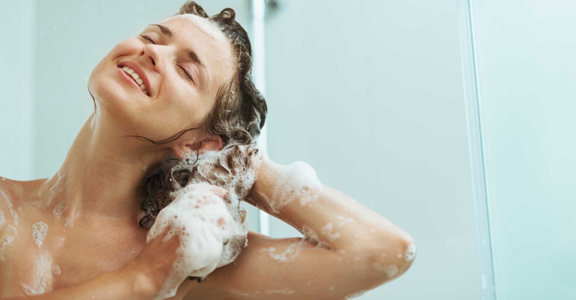 Modelo branca passando shampoo no cabelo