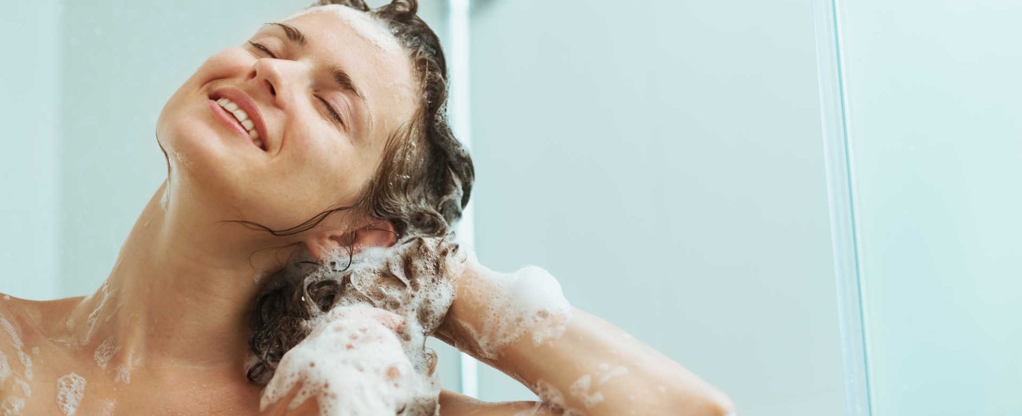 Modelo branca passando shampoo no cabelo