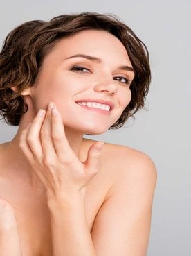 Modelo branca de cabelo curto passando creme no rosto