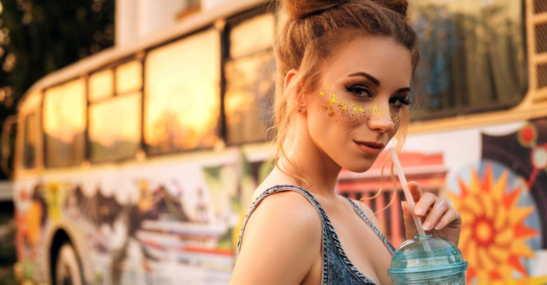 Modelo branca com glitter no rosto e cabelo amarrado