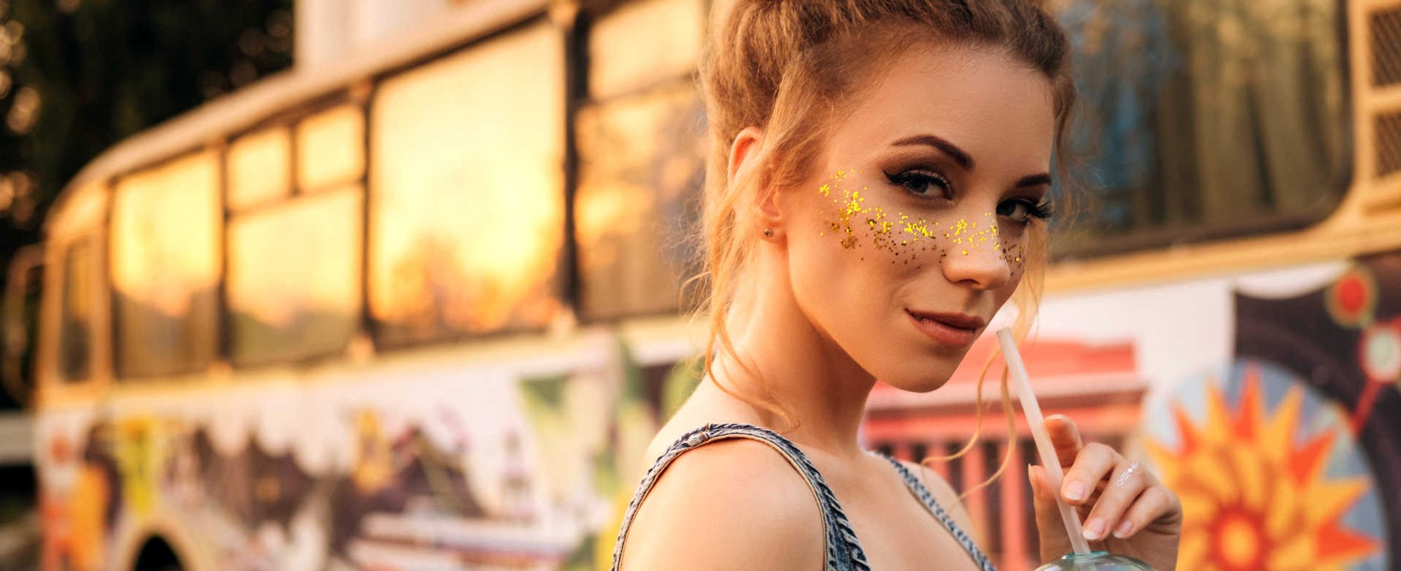 Modelo branca com glitter no rosto e cabelo amarrado