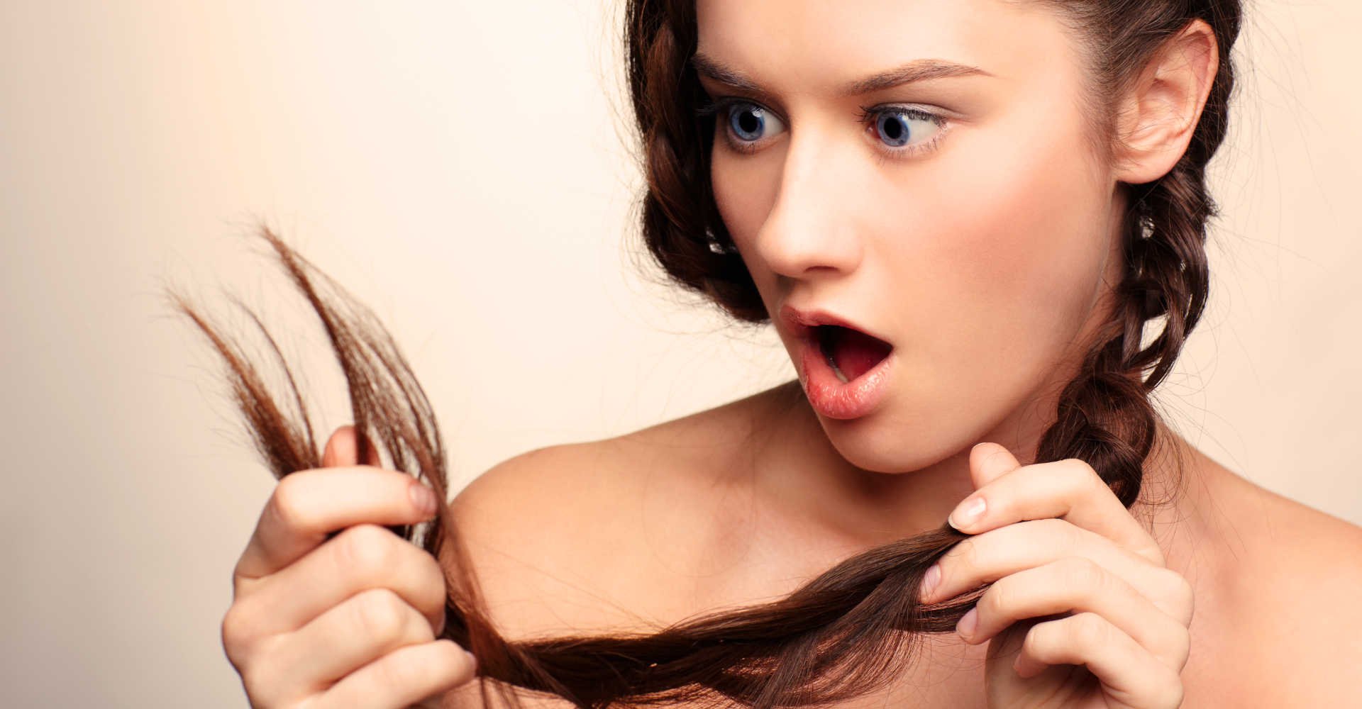 Modelo com expressão de surpresa analisando seus cabelos
