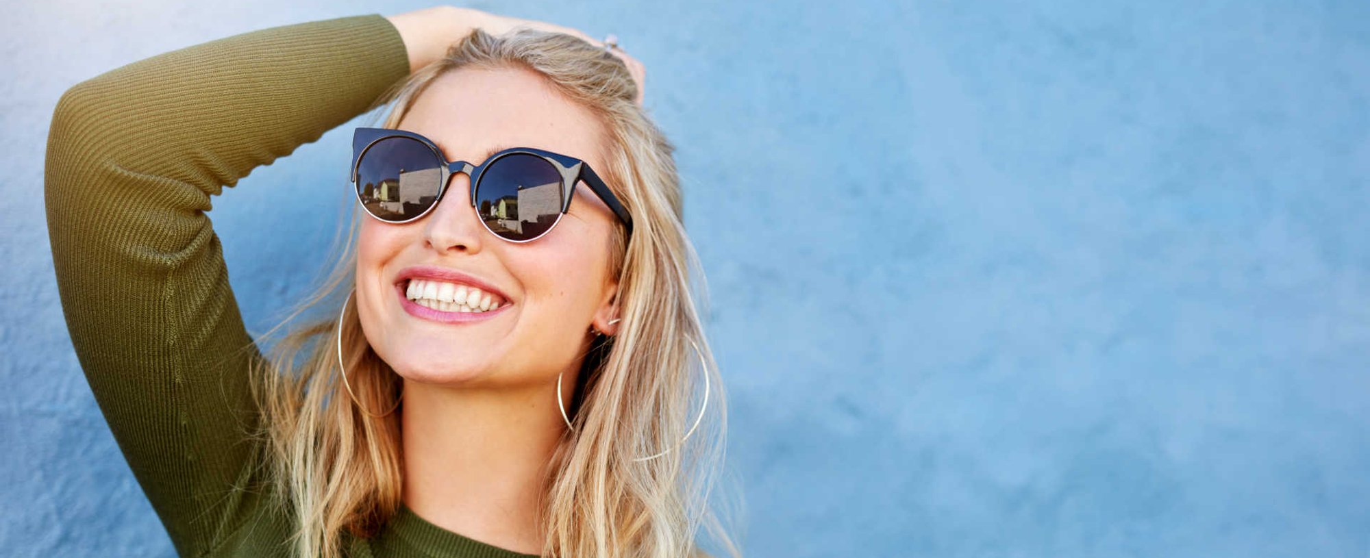 Modelo branca, de óculos de sol e sorrindo