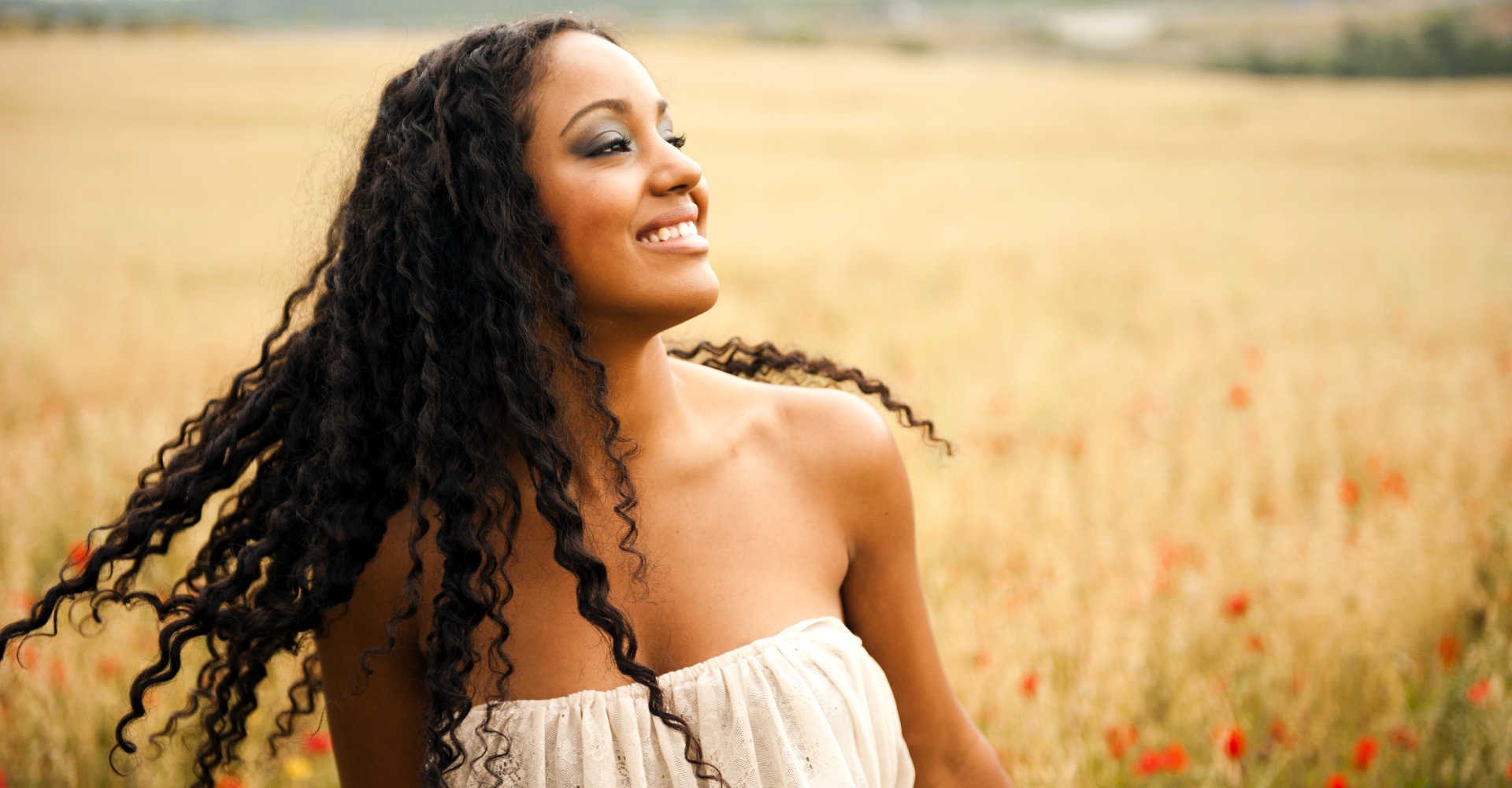 Modelo negra sorrindo com cabelo cacheado