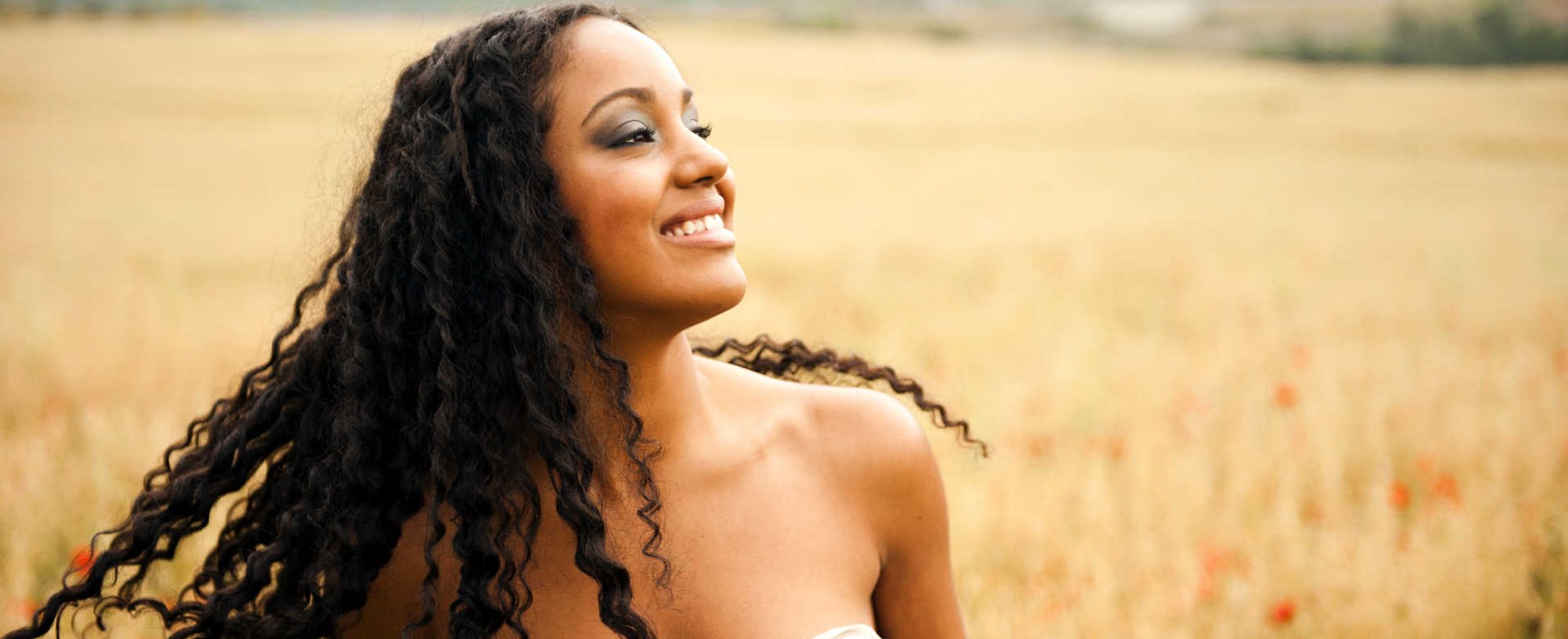 Modelo negra sorrindo com cabelo cacheado