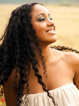 Modelo negra sorrindo com cabelo cacheado