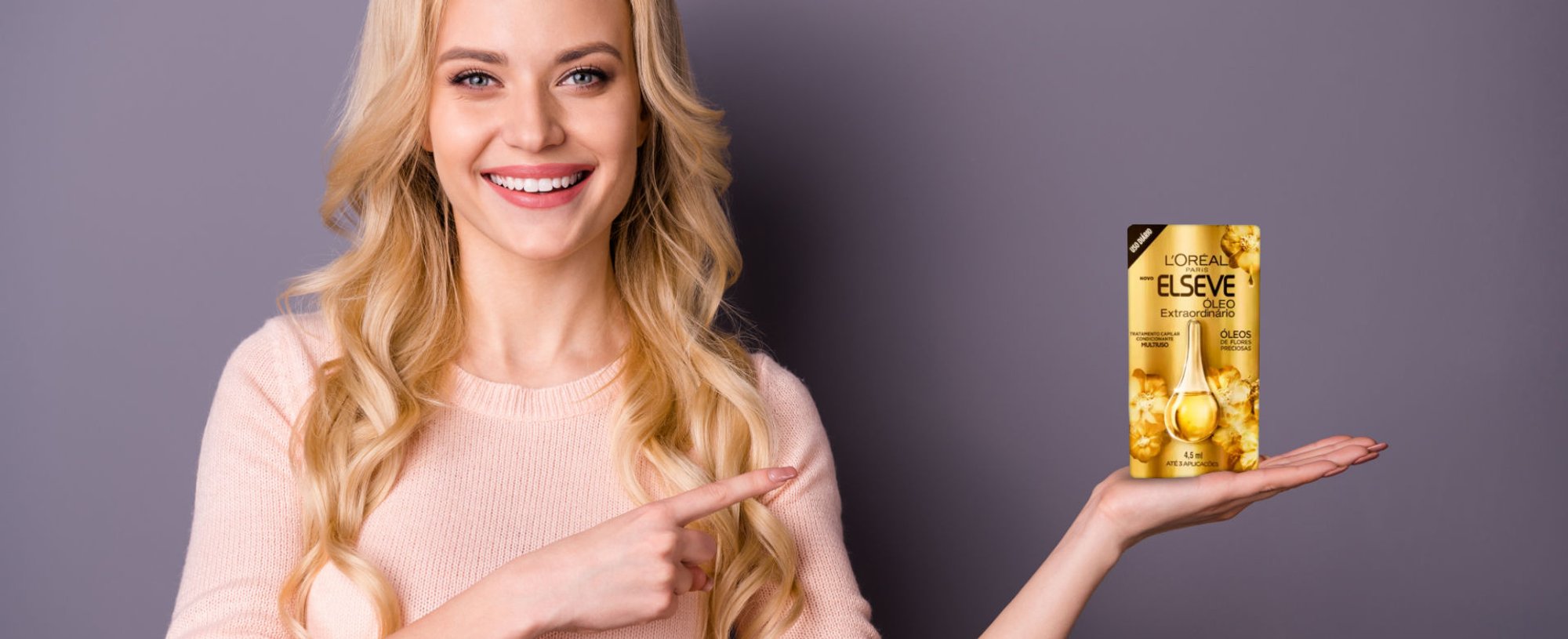 Modelo branca e loira com o produto Óleo Extraordinário na mão