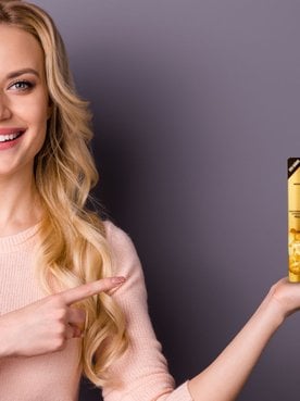 Modelo branca e loira com o produto Óleo Extraordinário na mão