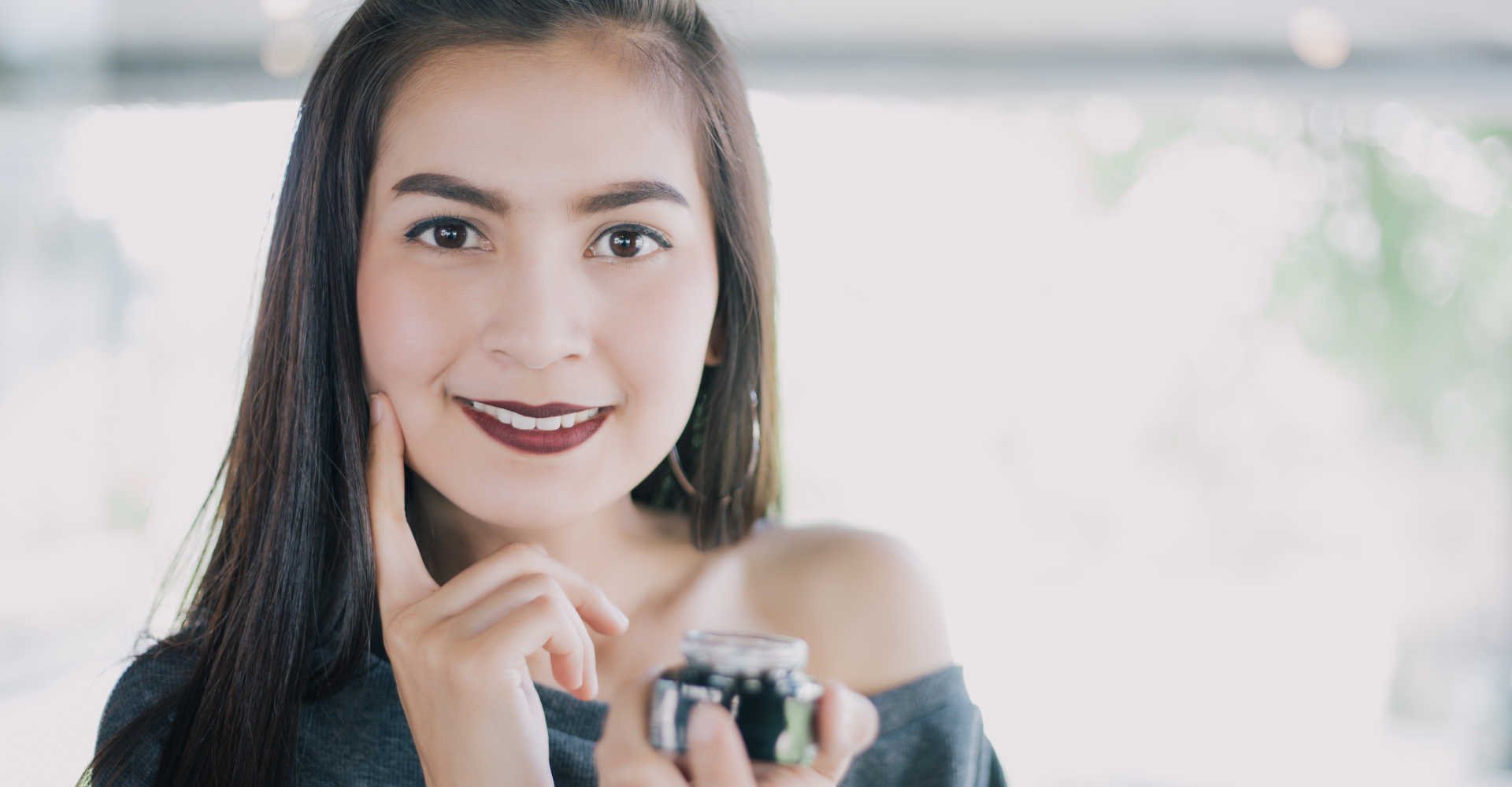 Modelo posando para a foto com um creme na mão