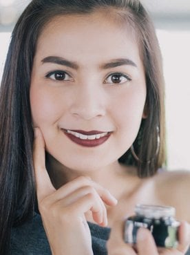 Modelo posando para a foto com um creme na mão