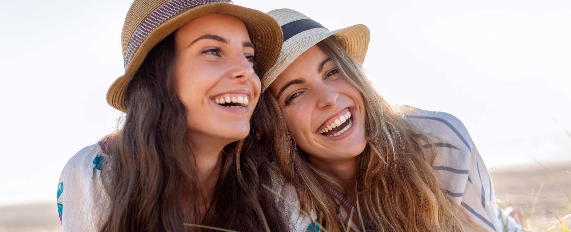duas mulheres deitada na praia com seus chapéus de acessórios de cabelo