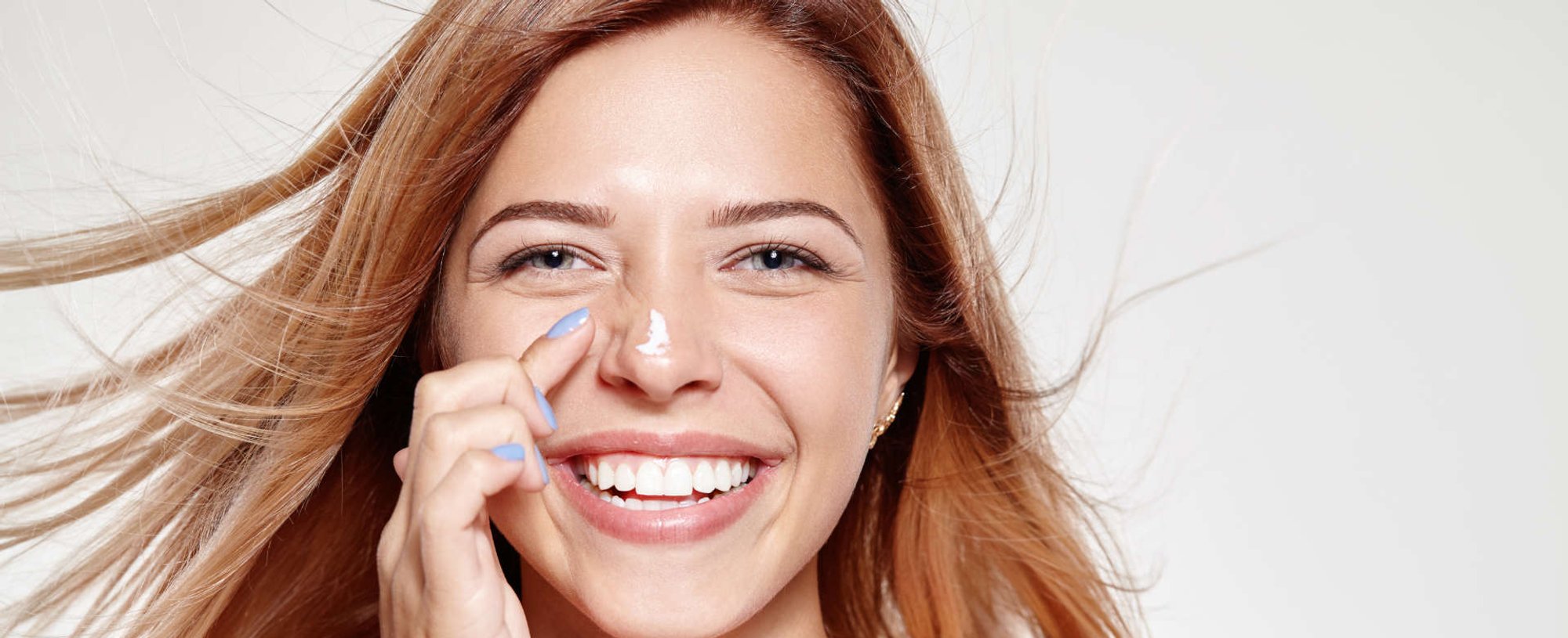 mulher passando protetor solar no rosto