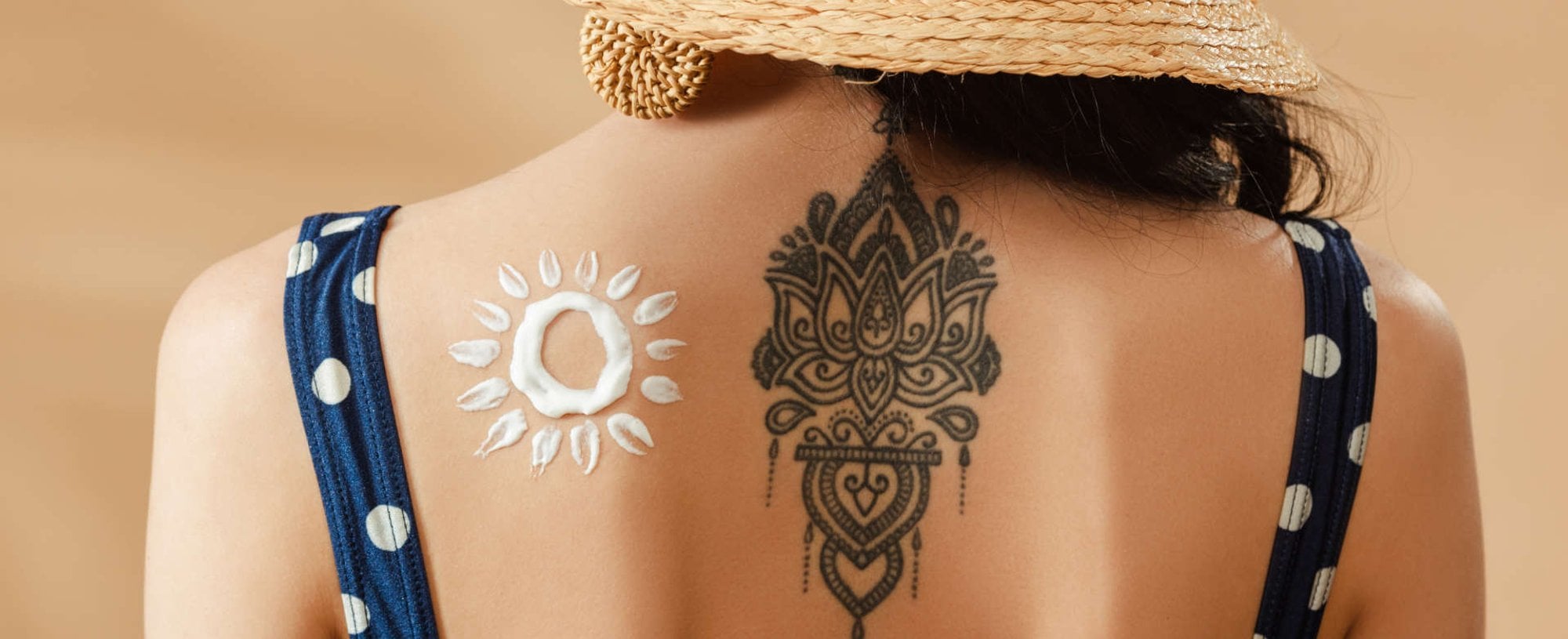 costas de uma mulher com tatuagem e ao lado protetor solar