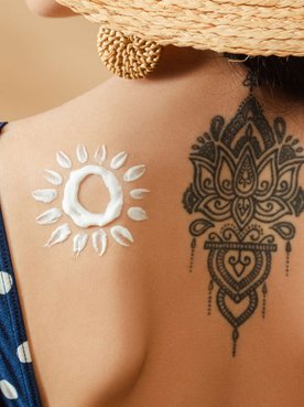 costas de uma mulher com tatuagem e ao lado protetor solar