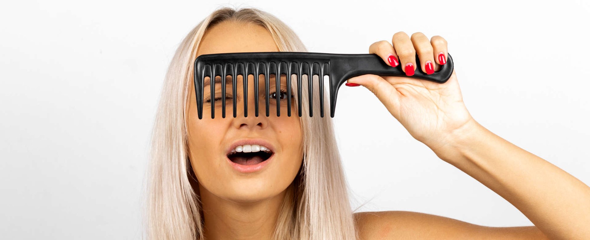 mulher exibe cabelo platinado segurando um pente na franja