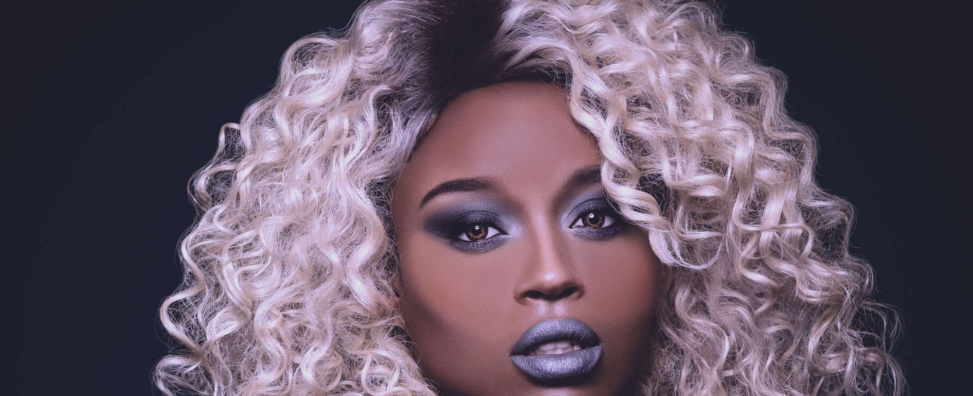mulher exibe seus cabelo cacheado na coloração platinada