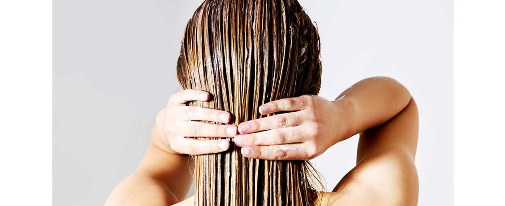 Modelo passando produto em seu cabelo de costas