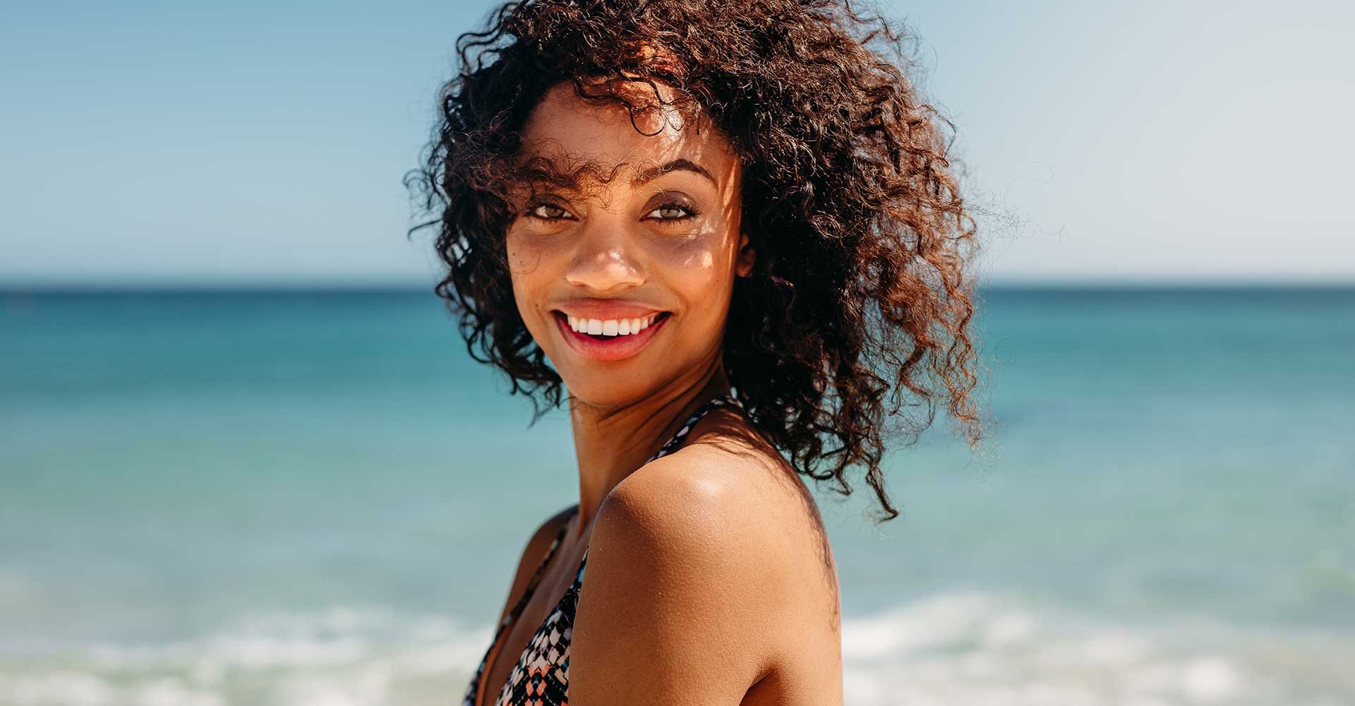 Modelo Morena Com Cabelo Cacheado Sorrindo Na Praia