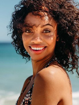 Modelo Morena Com Cabelo Cacheado Sorrindo Na Praia