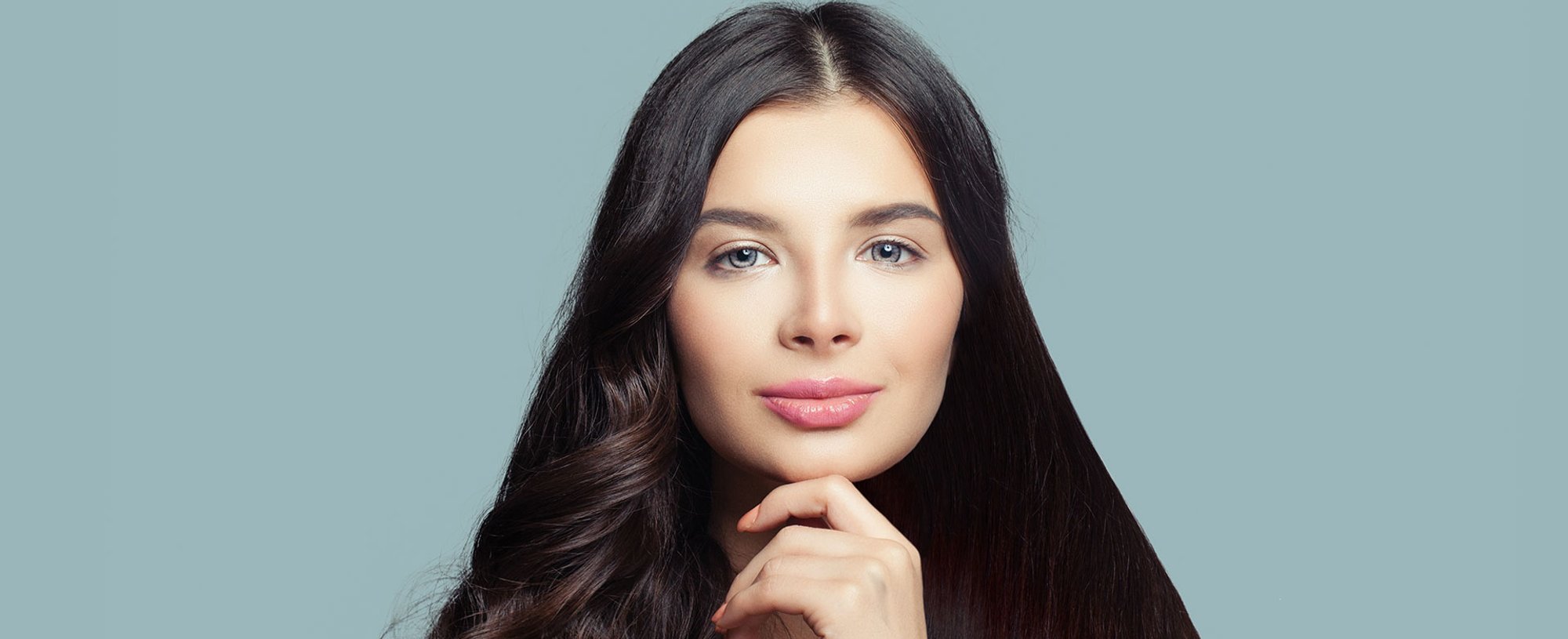 Modelo branca de olhos claros e cabelo preto comprido. Um lado liso e o outro ondulado