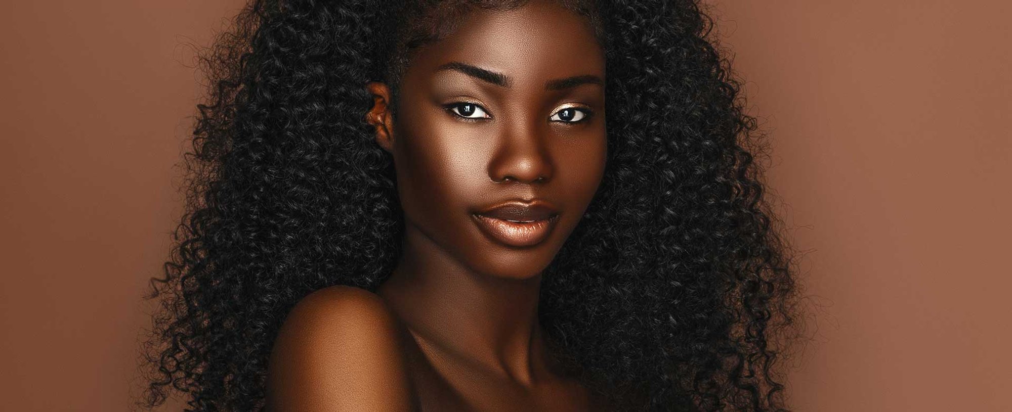 Mulher negra com o cabelo cacheado volumoso