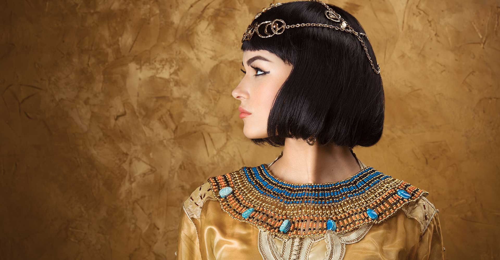 Imagem de uma modelo vestida de Cleópatra. Com uma roupa dourada e cabelo chanel