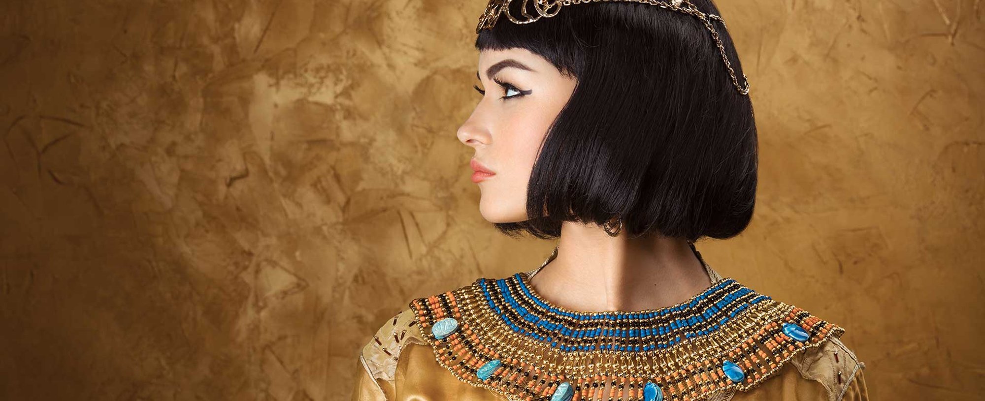 Imagem de uma modelo vestida de Cleópatra. Com uma roupa dourada e cabelo chanel