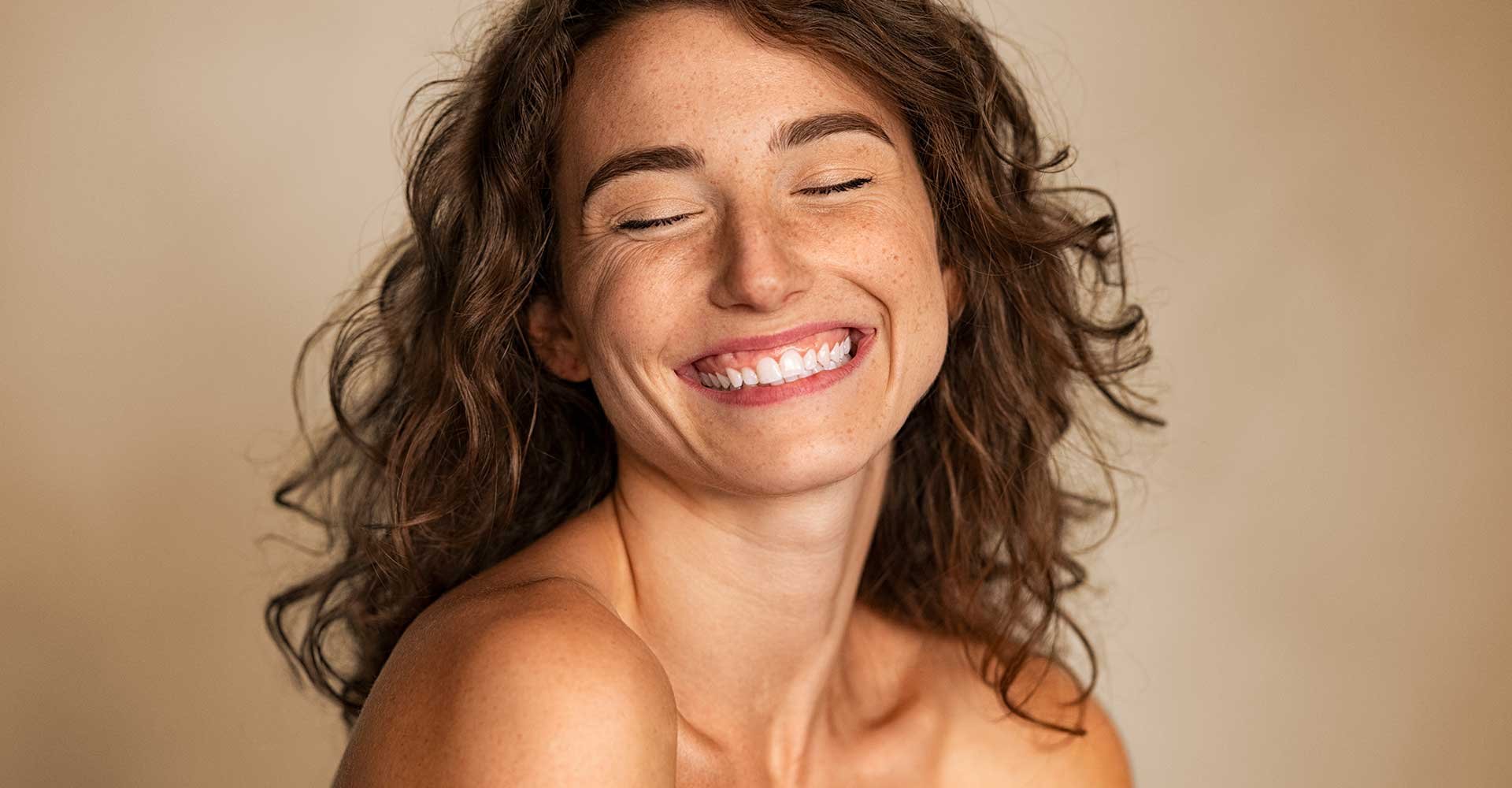 Modelo branca sorrindo com os olhos fechados