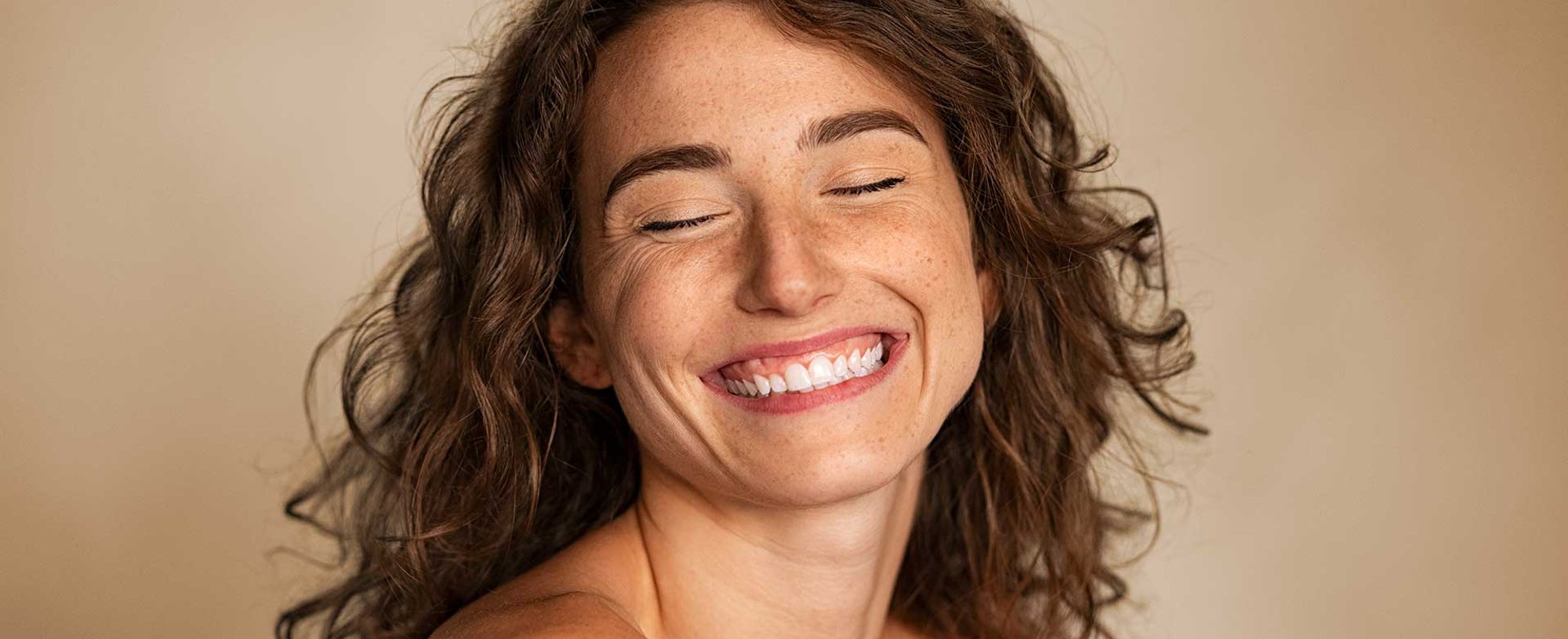 Modelo branca sorrindo com os olhos fechados