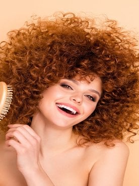 Mulher sorrindo com escova de pentear no cabelo