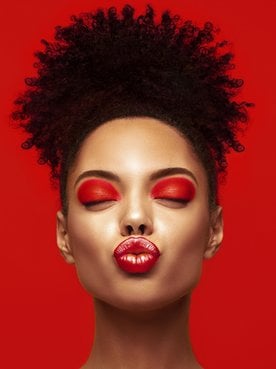 Imagem de mulher negra, com coque e fazendo biquinho.