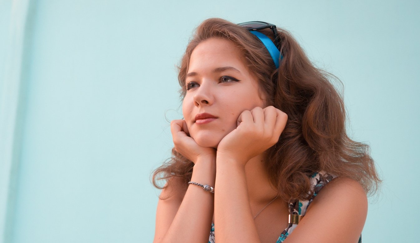 Imagem de mulher com cabelo estilo anos 60, com o queixo apoiado em suas mãos.